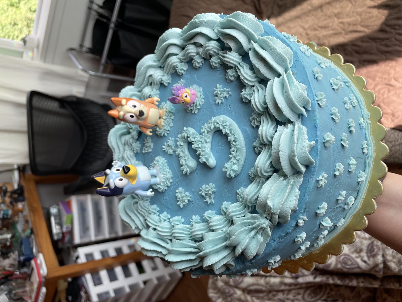 Blue birthday cake with character toppers and piped buttercream border