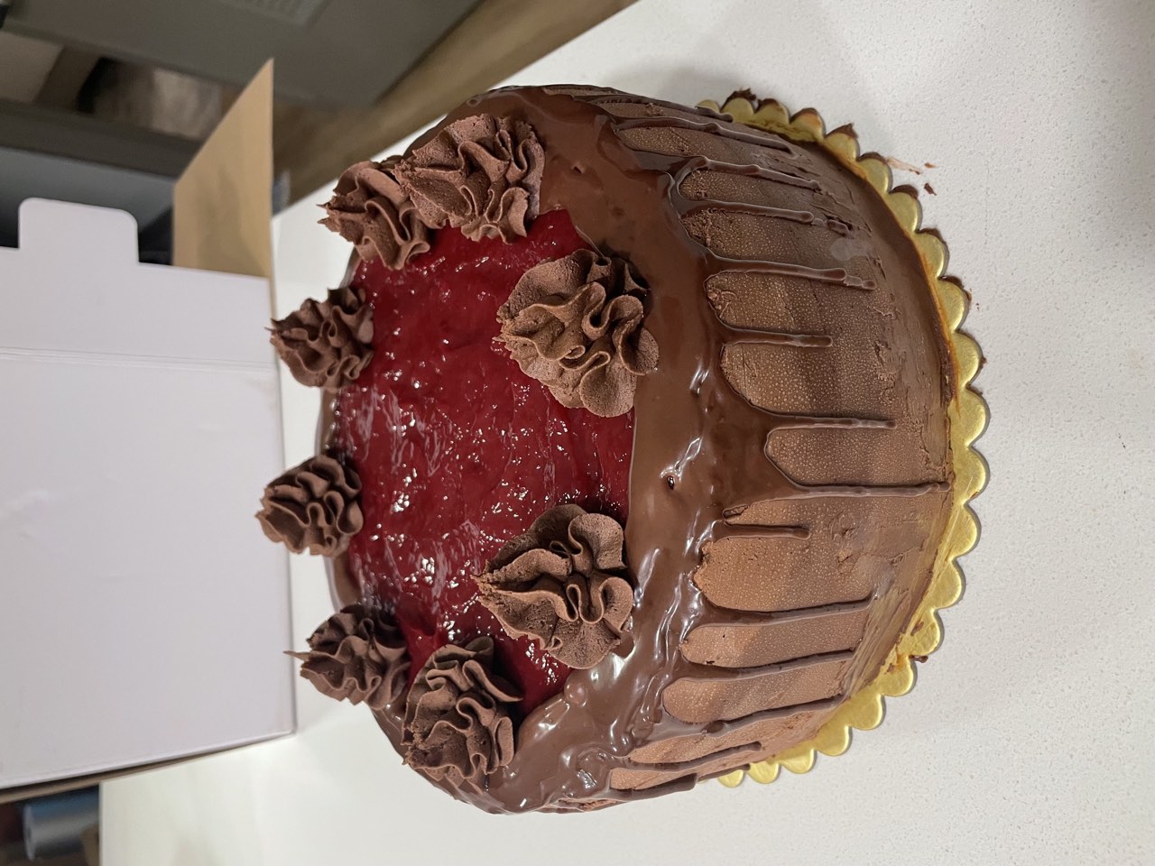 Chocolate drip cake topped with raspberry filling and chocolate buttercream