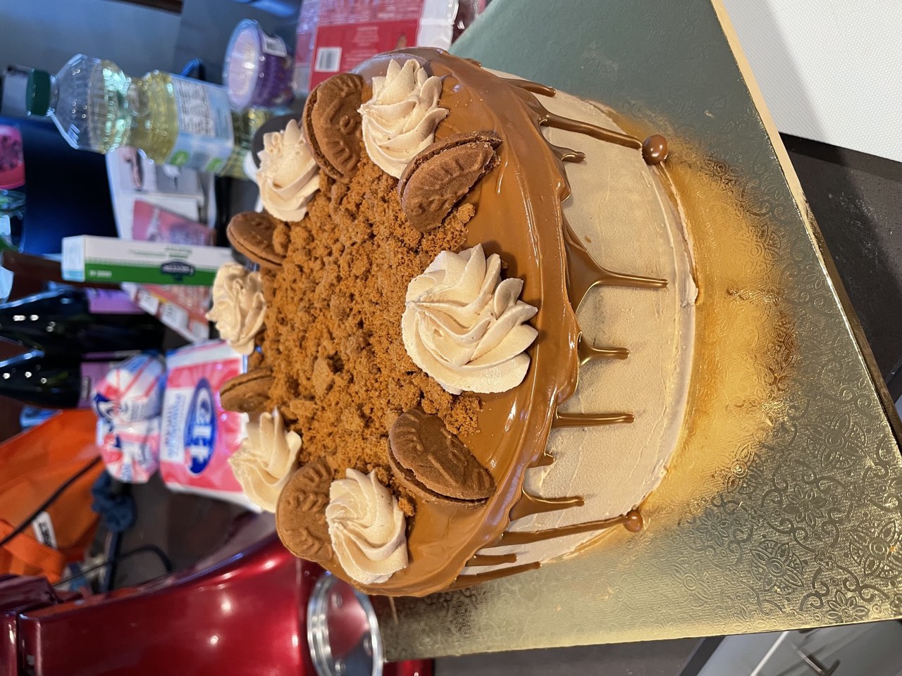 Caramel drip cake topped with cookie crumbs and buttercream swirls